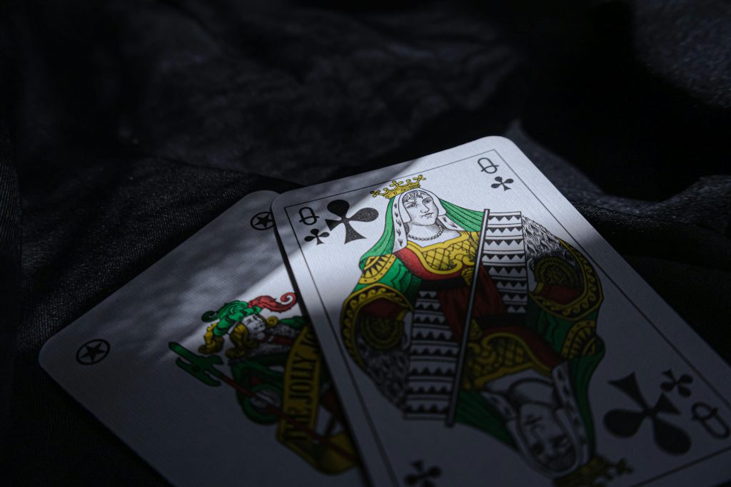 Close-up of queen of clubs playing cards on a dark surface, emphasizing a casino theme.
